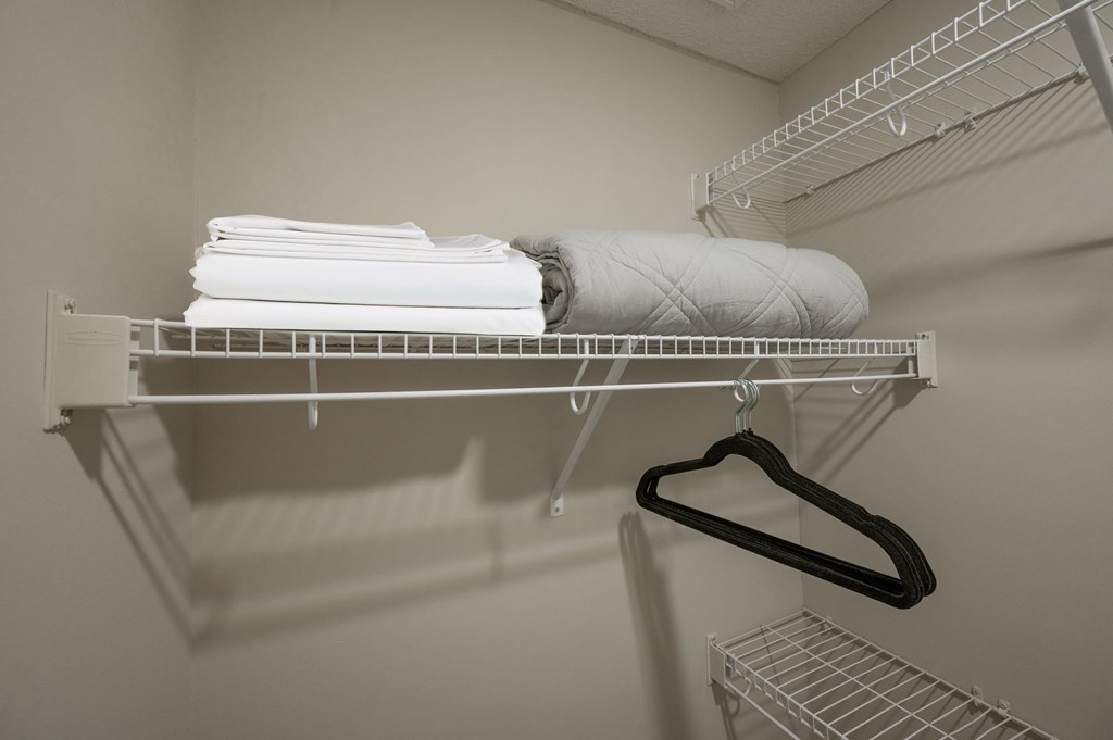 A white shelf with a hanger and towels on it.