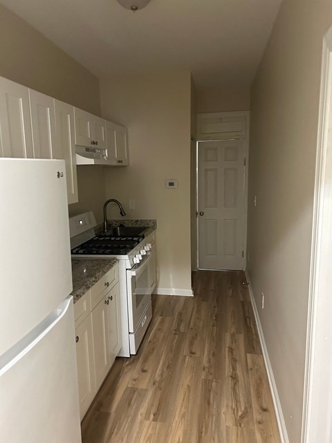 A kitchen with white cabinets and a white refrigerator.