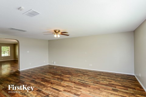 the spacious living room with wood flooring and a ceiling fan