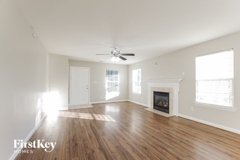 A spacious room with a fireplace and a ceiling fan.