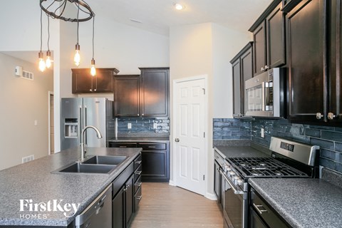 a kitchen with black cabinets and granite counter tops and a sink