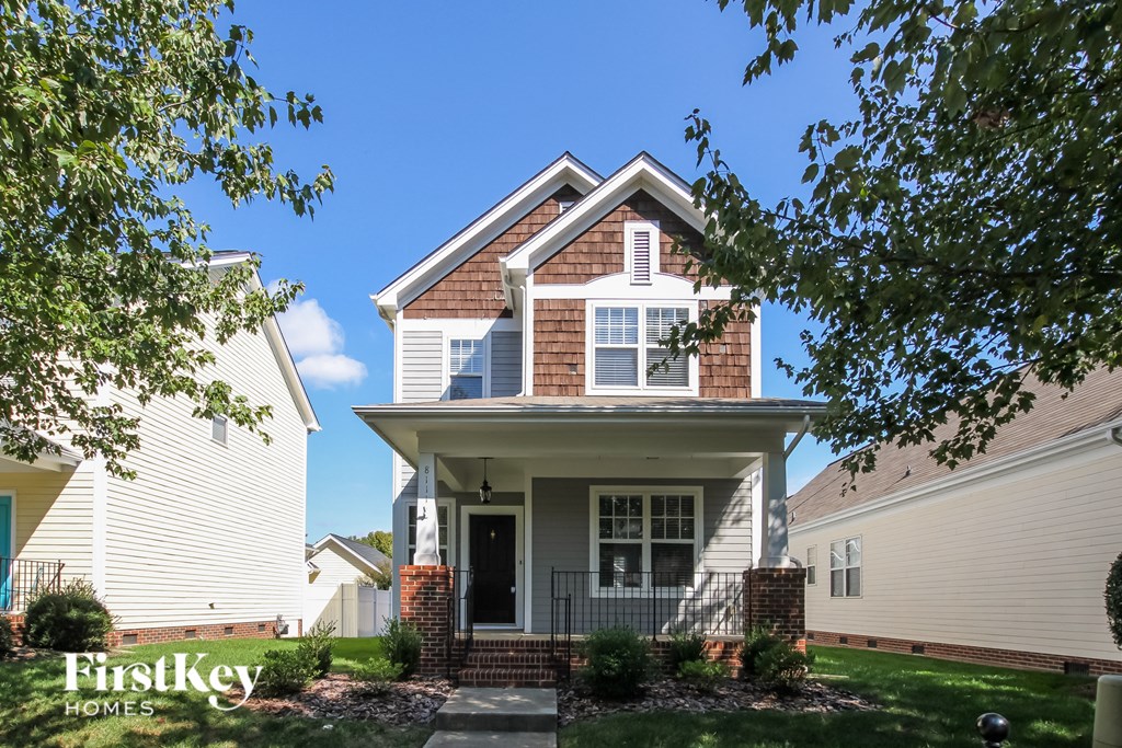 A house with a white front porch and a brick pillar.