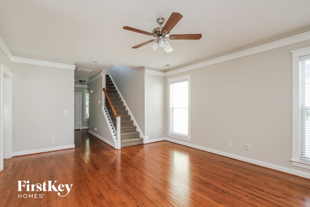 A spacious room with a staircase and a ceiling fan.