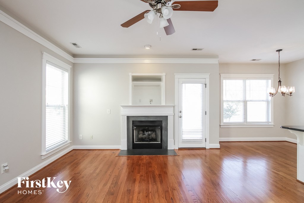 A spacious living room with a fireplace and a ceiling fan.