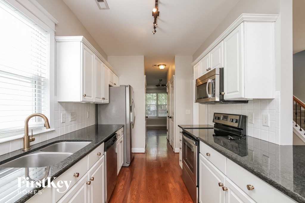 A kitchen with white cabinets and black countertops.