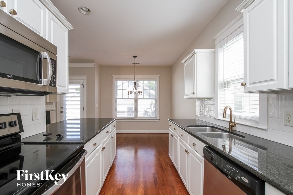 A kitchen with white cabinets and a black counter top.