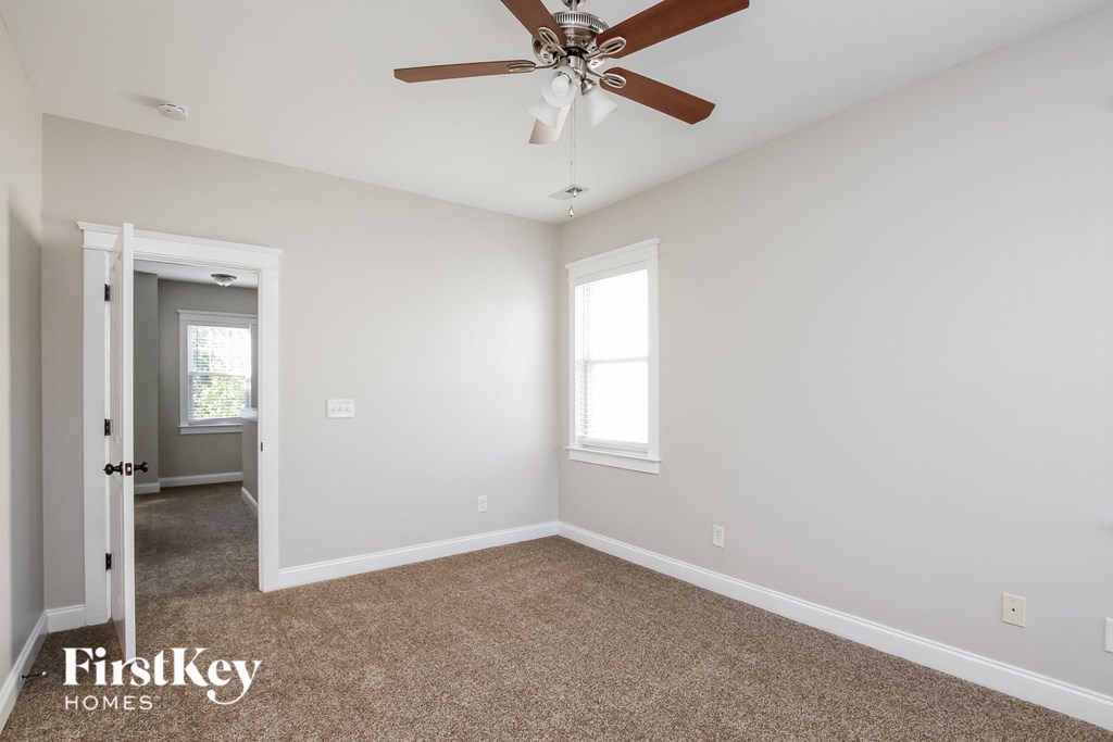 A room with a carpeted floor and a ceiling fan.