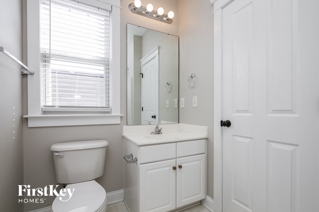 A white bathroom with a toilet, sink, and mirror.