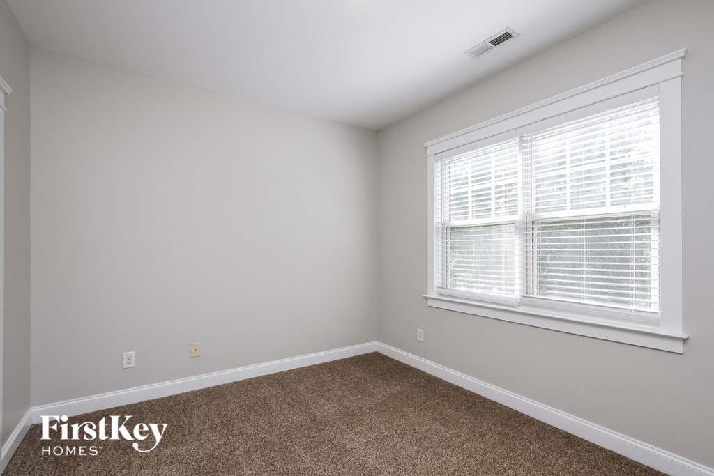 A room with a carpeted floor and a window with blinds.