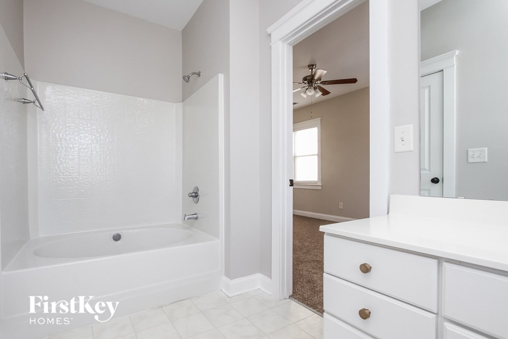 A white bathroom with a tub, sink, and mirror.