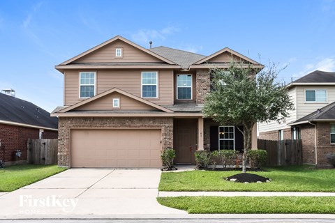 A two-story house with a garage and a tree in front.