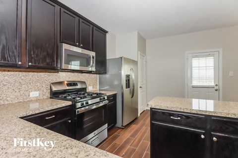A kitchen with black cabinets and a granite countertop.