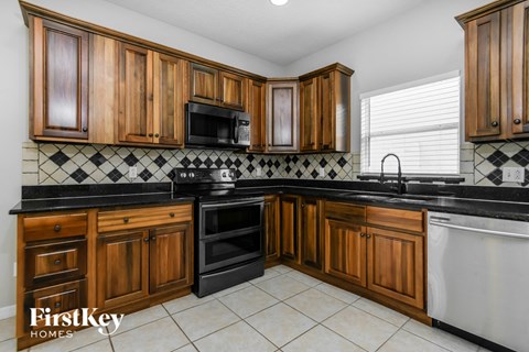 a kitchen with black counter tops and wooden cabinets