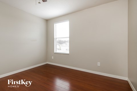 a bedroom with wood floors and a window