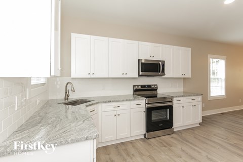A kitchen with white cabinets and a marble countertop.