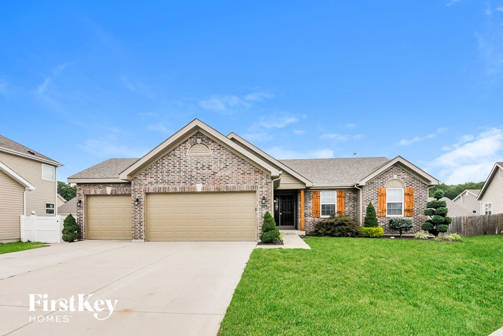 a brick house with a garage and a green lawn