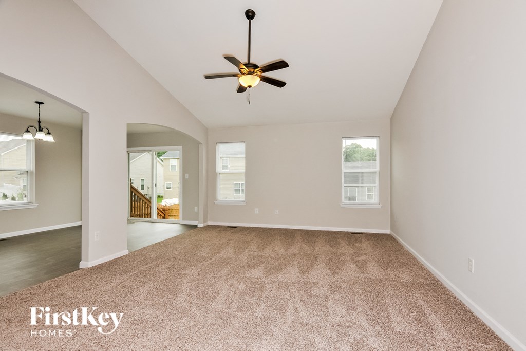 an empty living room with a ceiling fan and a carpet