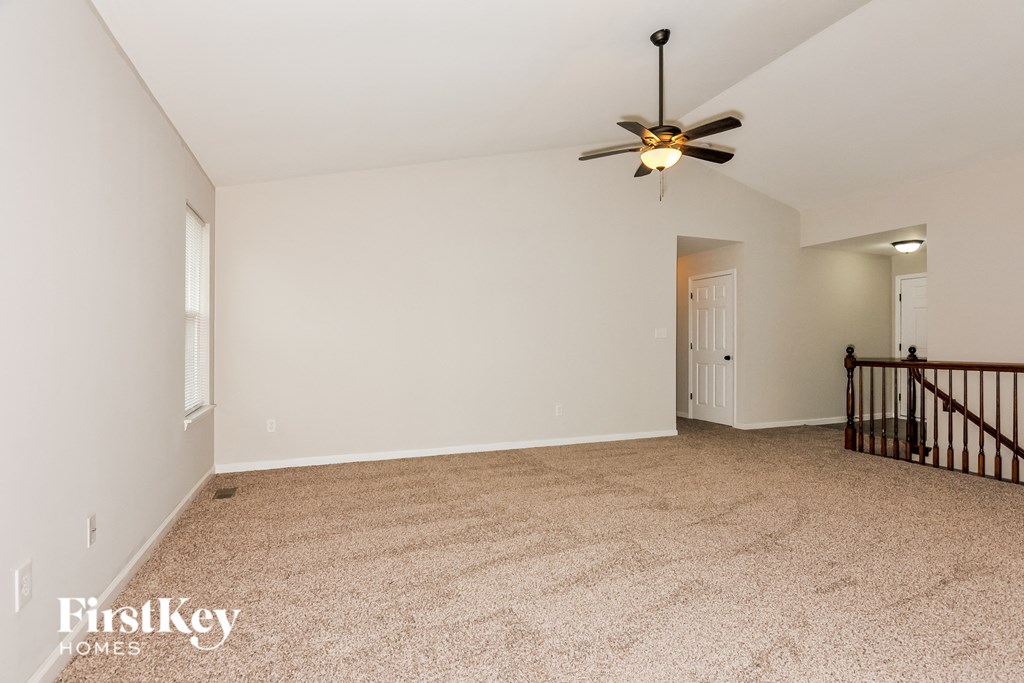 a spacious living room with carpet and a ceiling fan