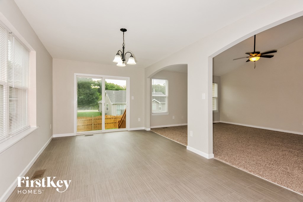 an empty living room and dining room with wood floors and a ceiling fan