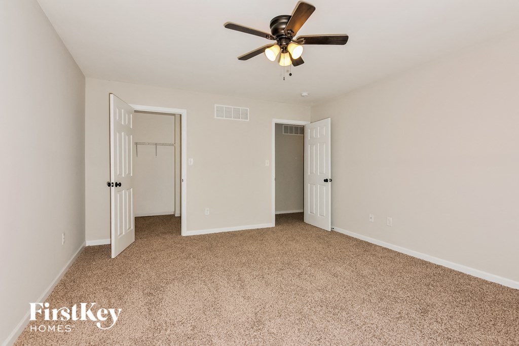 a master bedroom with carpet and a ceiling fan
