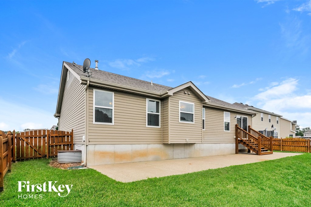 a home with a wooden fence and a yard with green grass