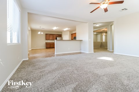 A spacious living room with a ceiling fan and a carpeted floor.