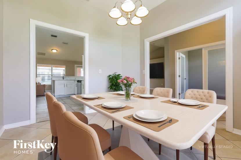 A dining room with a table set for two and a chandelier hanging from the ceiling.