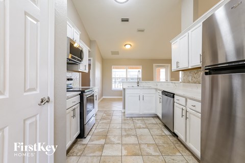 A kitchen with a stainless steel refrigerator and white cabinets.