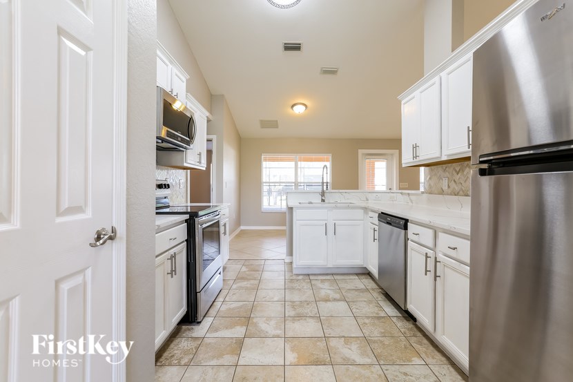 A kitchen with a stainless steel refrigerator and white cabinets.