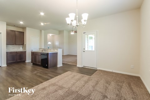 A spacious living room with a kitchen in the background and a rug on the floor.