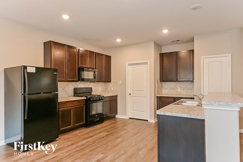 a kitchen with wood flooring and stainless steel appliances and wooden cabinets