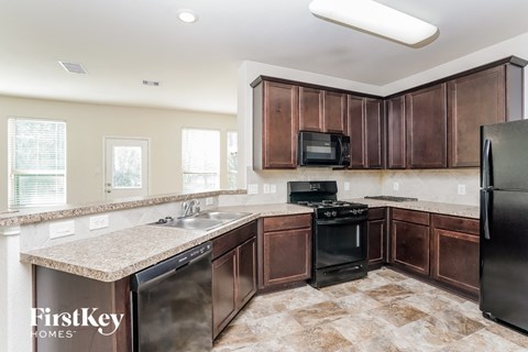 A kitchen with brown cabinets and a black refrigerator.