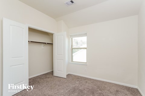 A bedroom with a carpeted floor and a window.