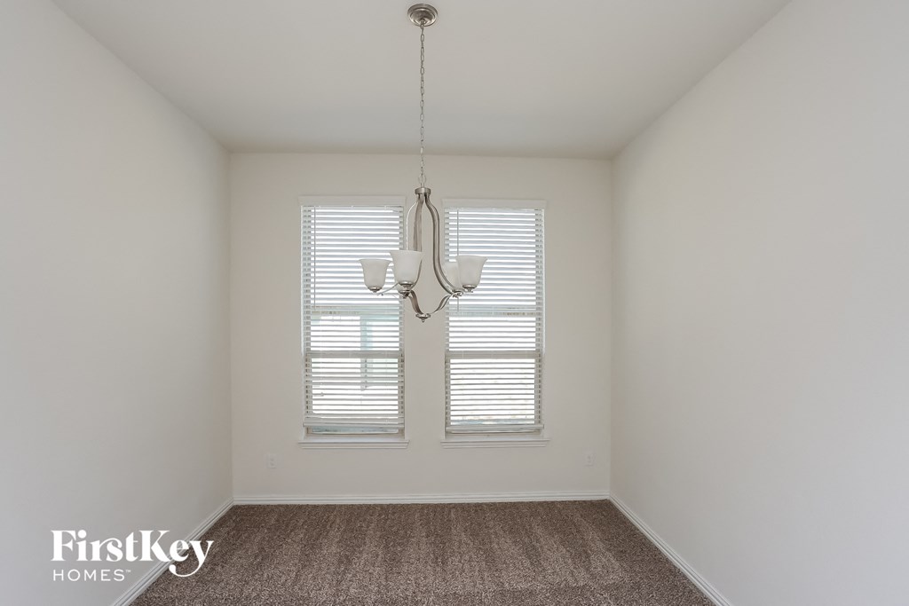 an empty room with a chandelier and two windows