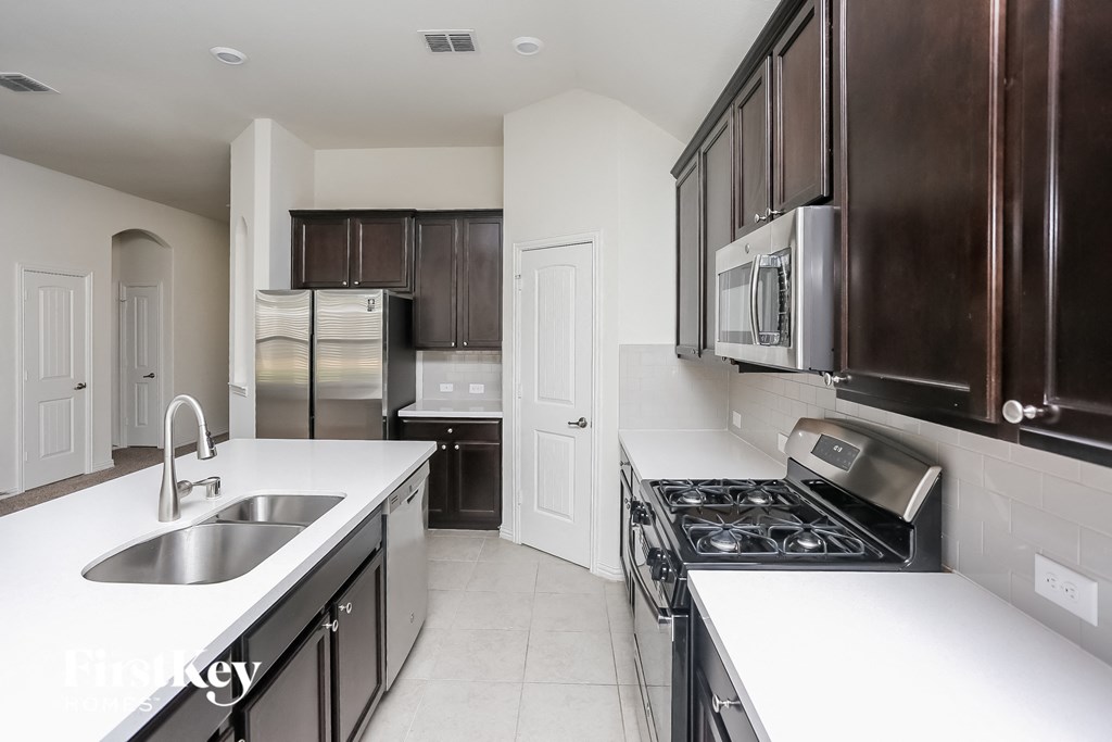 a kitchen with white counters and black cabinets and stainless steel appliances