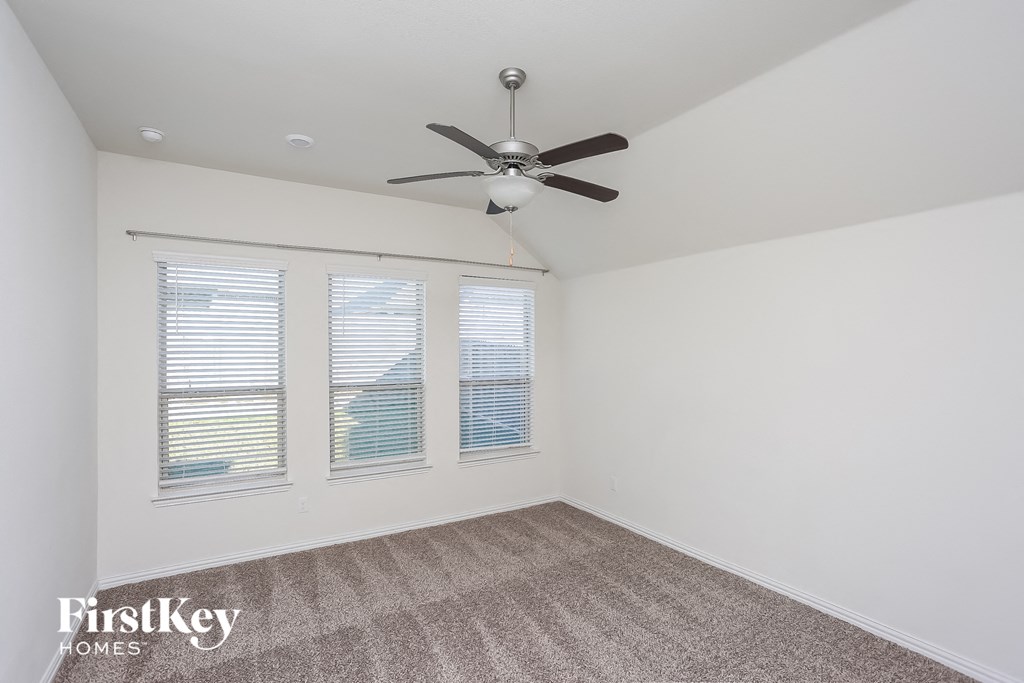 a bedroom with three windows and a ceiling fan