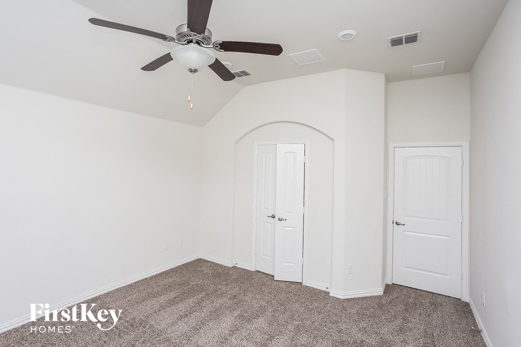 a bedroom with white walls and a ceiling fan