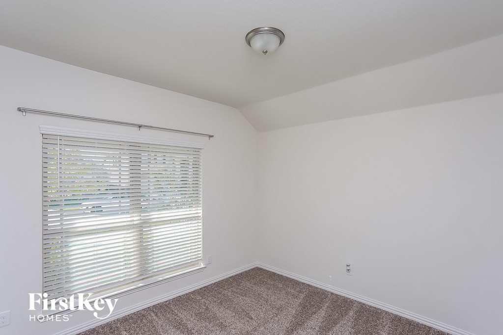 a bedroom with white walls and a window with blinds