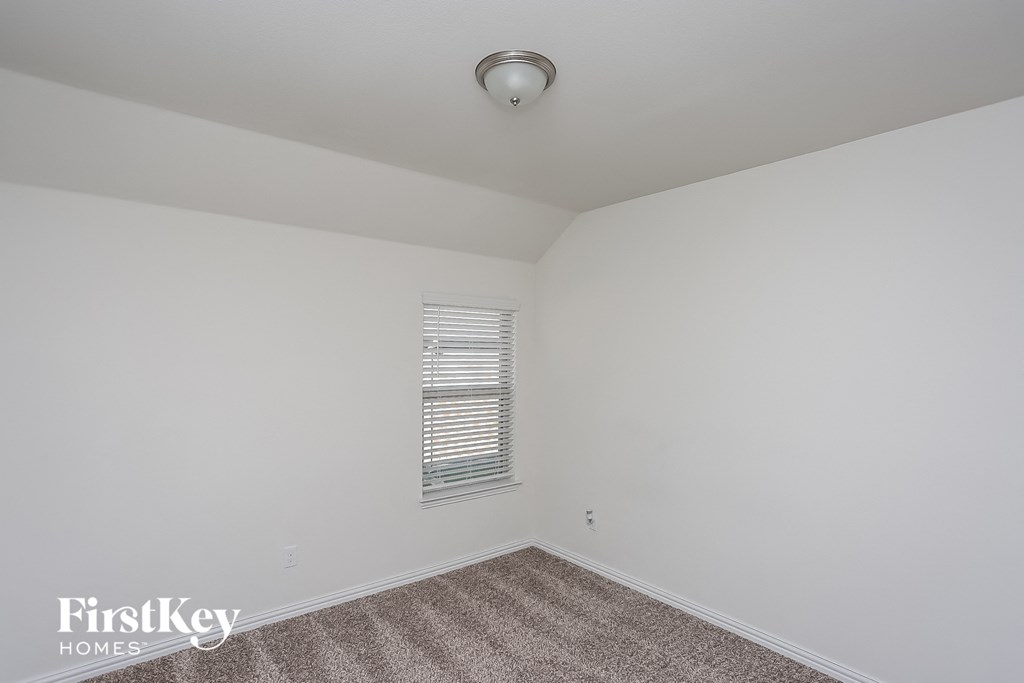 a bedroom with white walls and carpet and a window