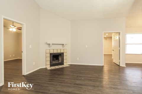 A spacious room with a fireplace and wooden floors.