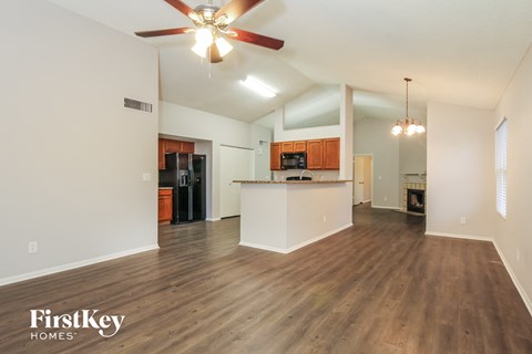 A spacious living room with a ceiling fan and wooden flooring.