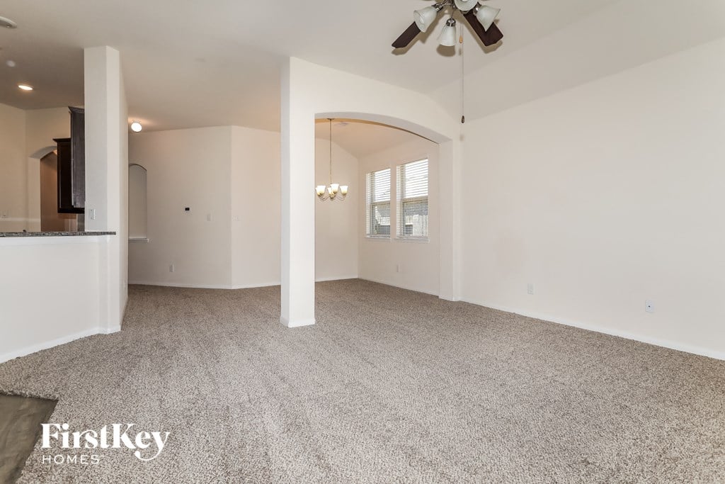 an empty living room with carpet and a ceiling fan