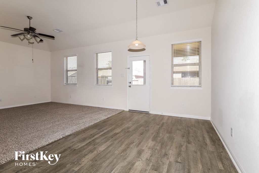 a living room with white walls and wood floors and a ceiling fan