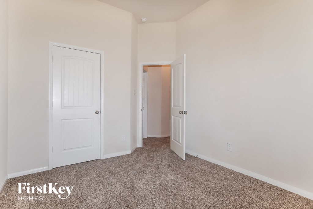 a bedroom with white walls and carpet and a door to a closet