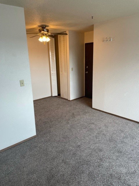 an empty living room with a ceiling fan