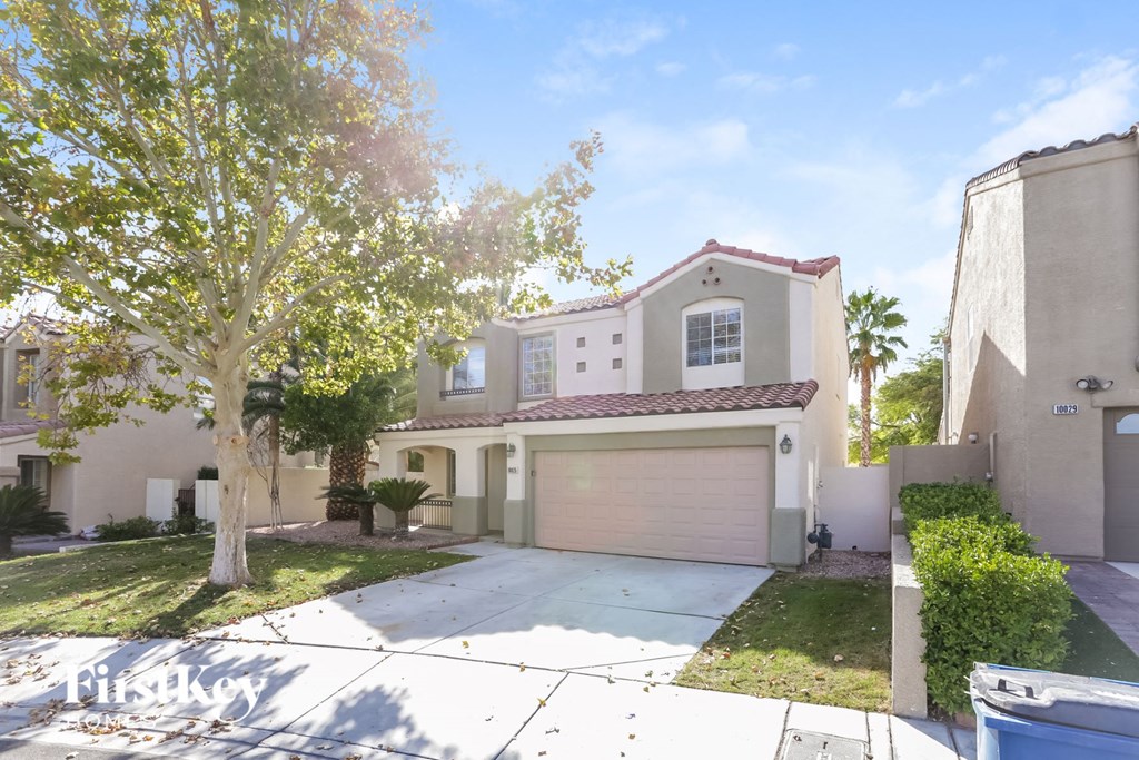 a beige house with a garage and a tree