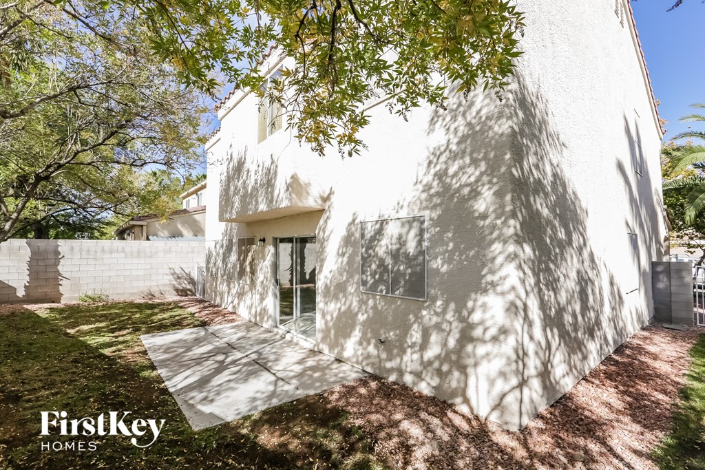 a side view of a white house with a sidewalk and a tree