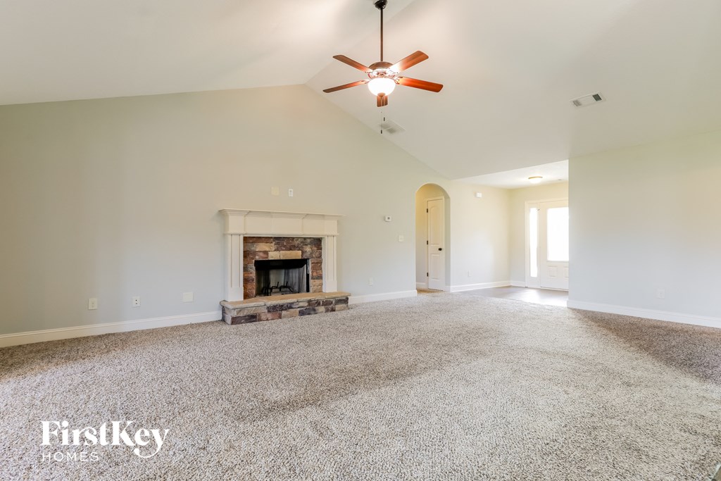 A spacious living room with a fireplace and a ceiling fan.