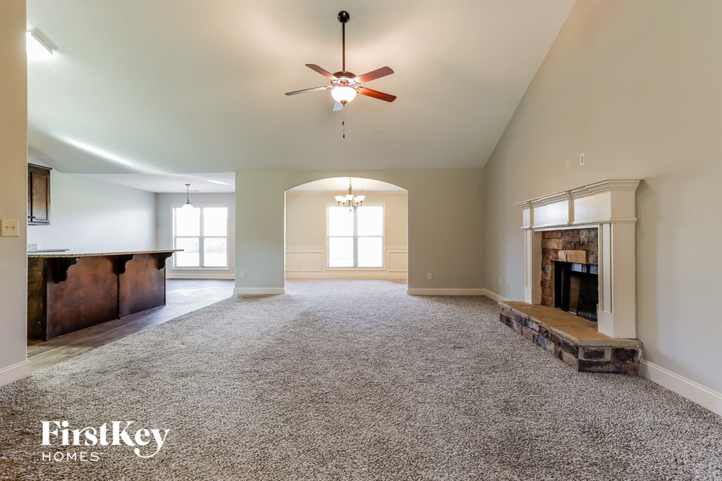 A spacious living room with a fireplace and a ceiling fan.