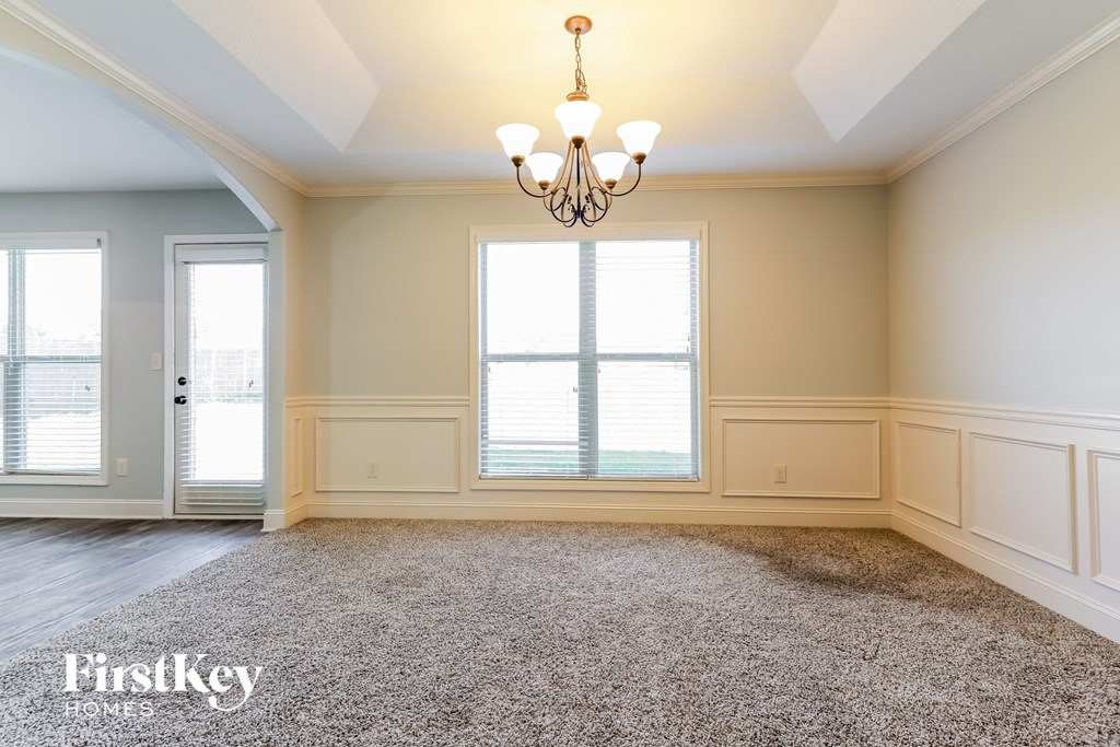 A spacious room with a chandelier and a carpeted floor.